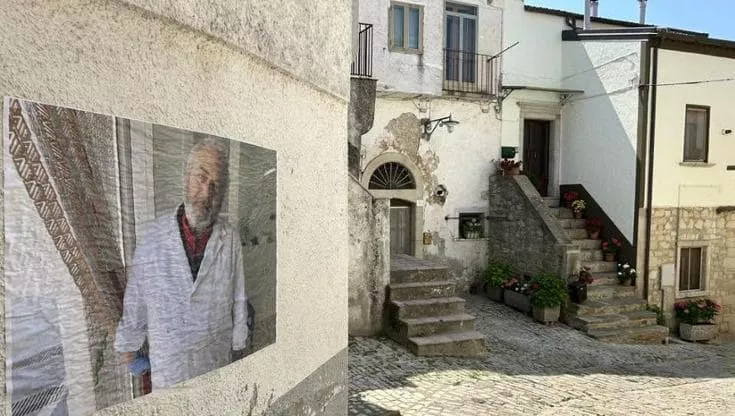 Una gigantografia con il volto di un abitante affissa su un muro nei vicoli di Orsara di Puglia